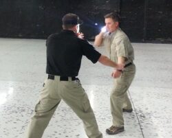 2 People facing each other using a flashlight for self defense