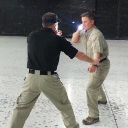 2 People facing each other using a flashlight for self defense