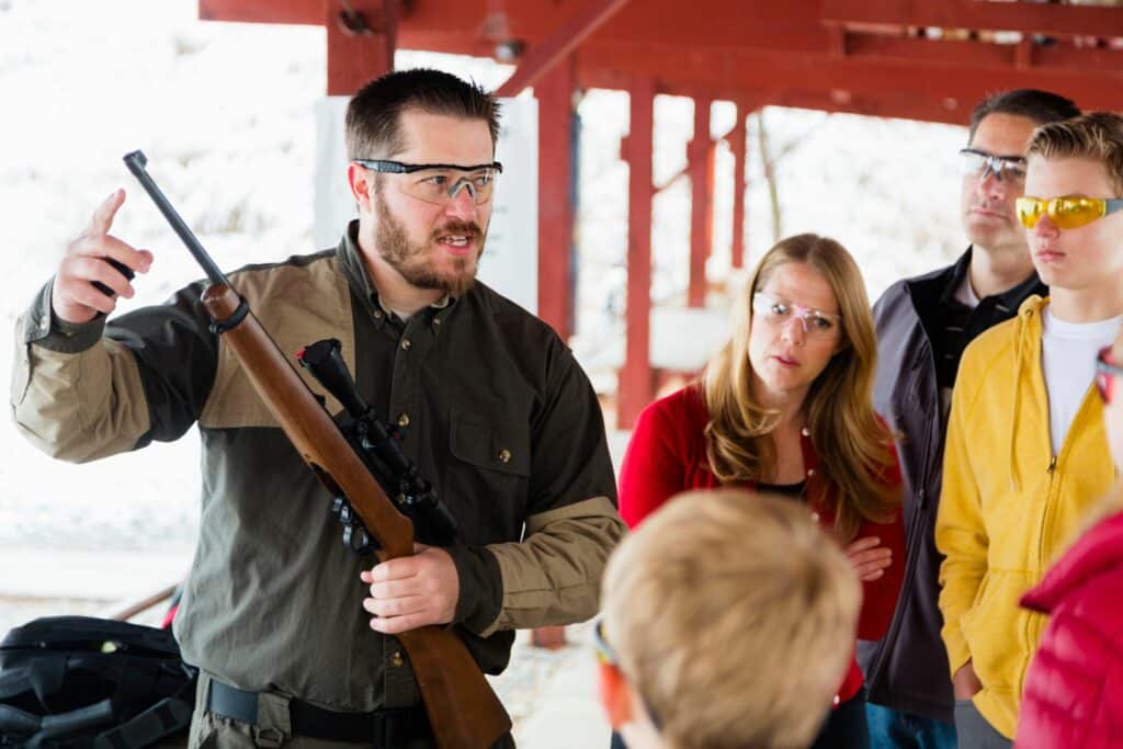 A firearm instructor talking about a firearm to kids